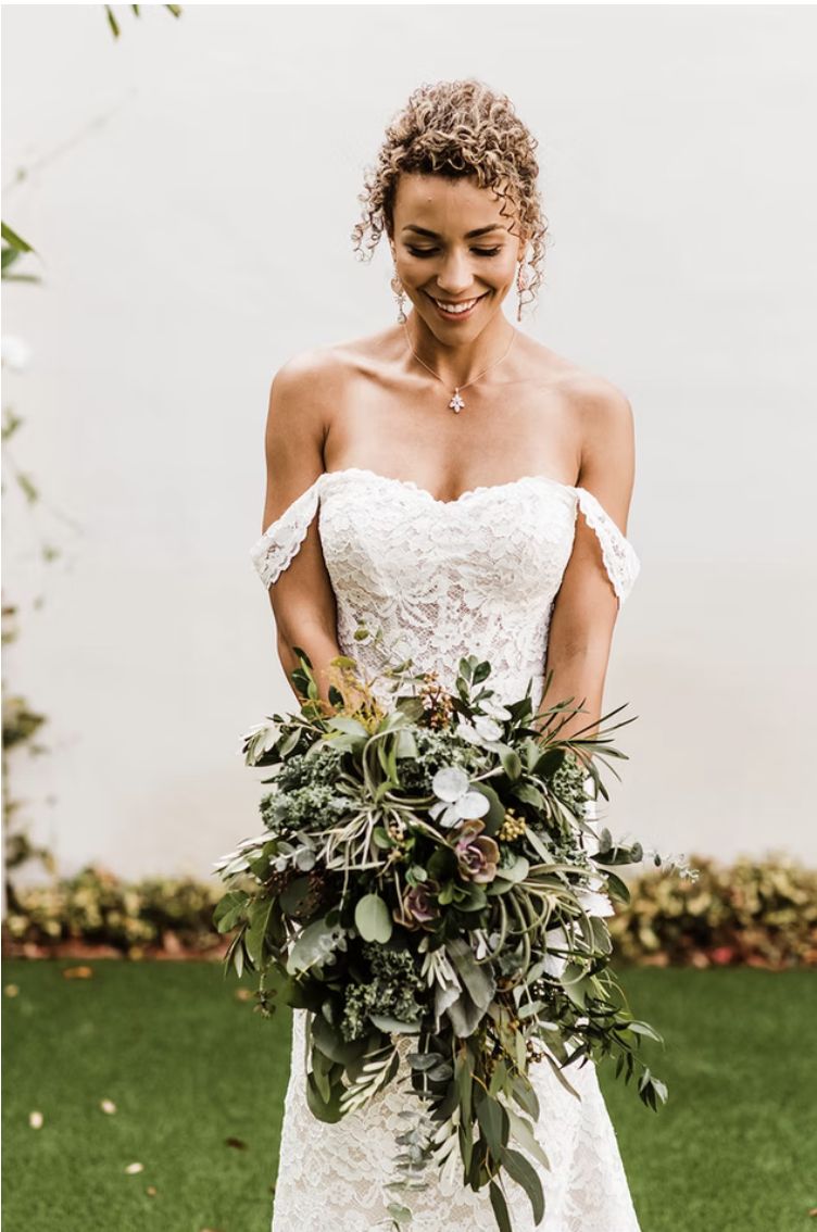 A bride with her bouquet against a white wall