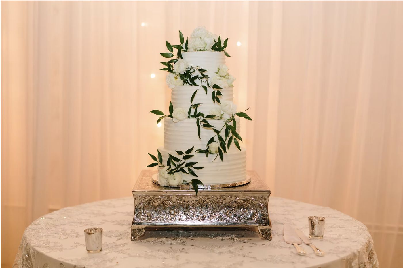 A tiered wedding cake trimmed with greenery