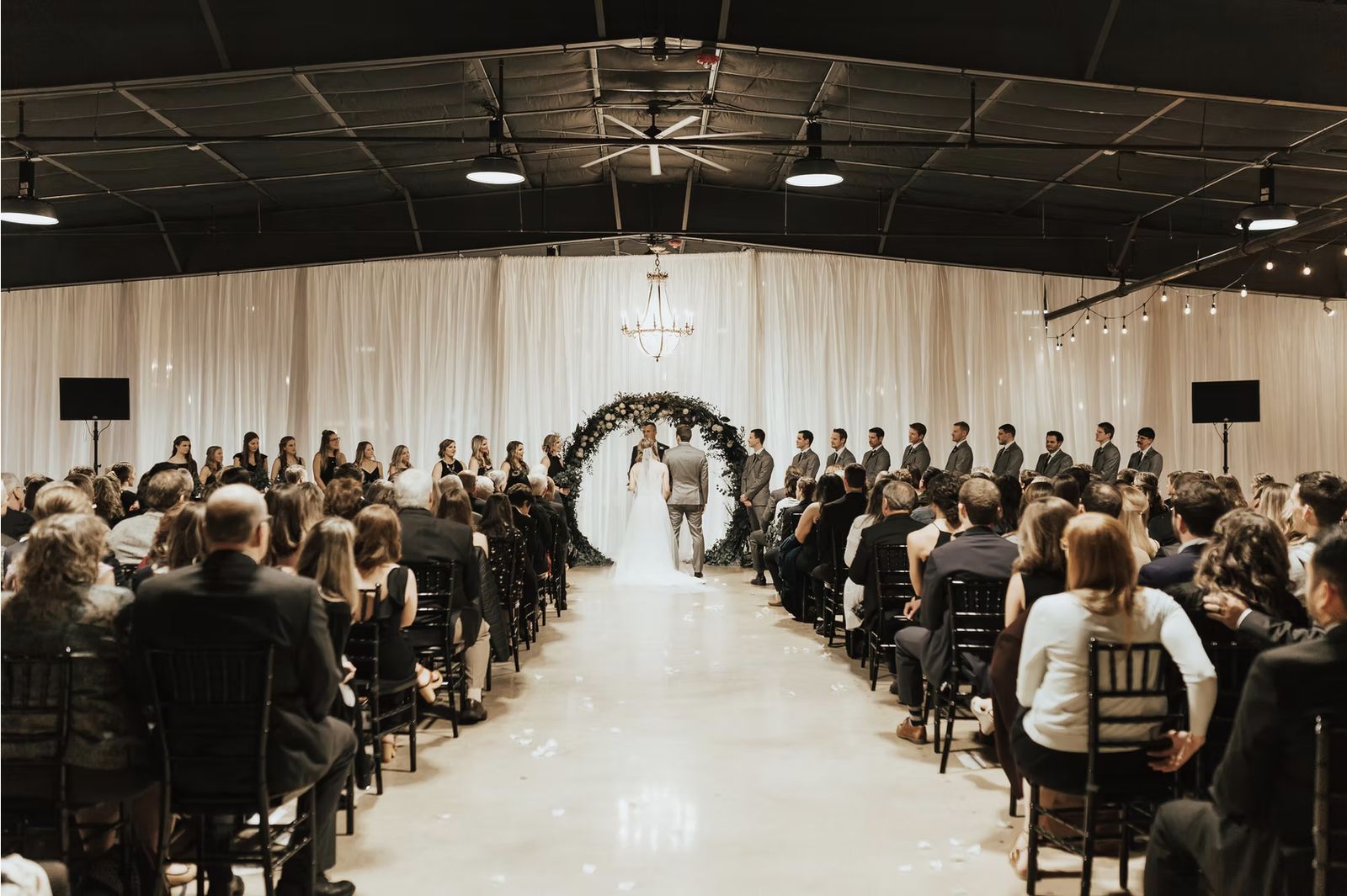 The main hall at Venue 650 set for a ceremony with a draped arch and a full house of guests
