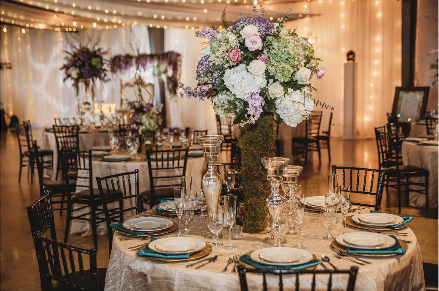 A round table at Venue 650 dressed with linen, place settings and a tall floral centrepiece